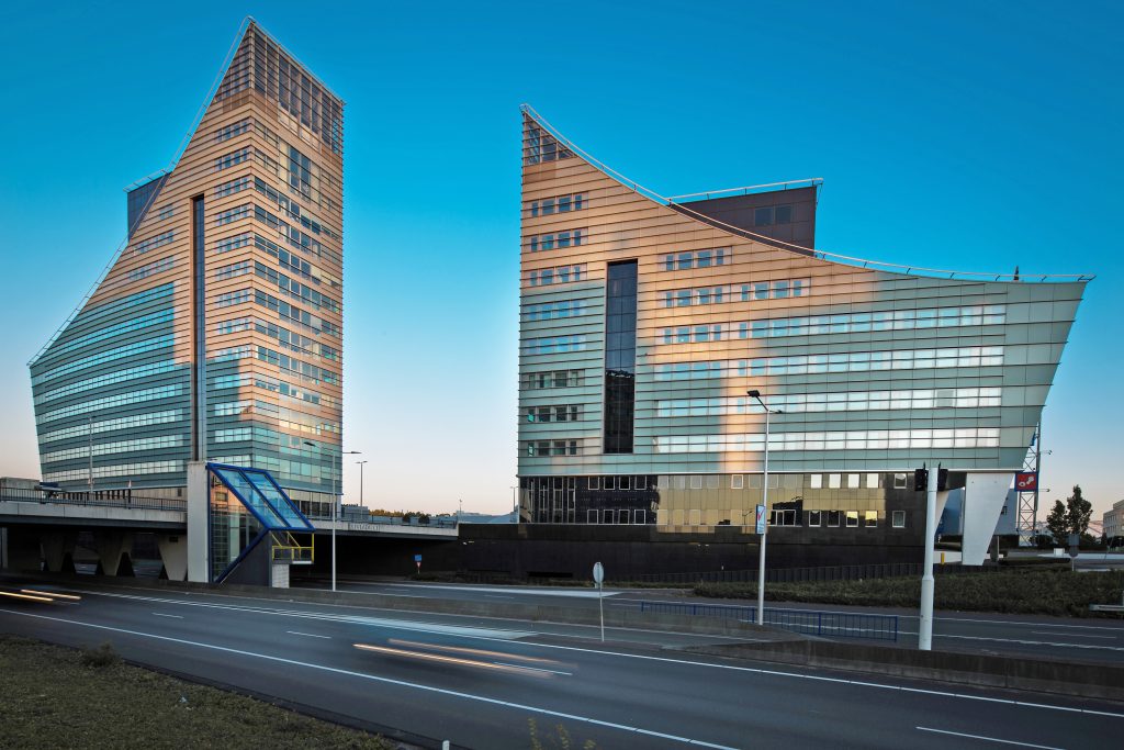 two tall buildings sitting next to each other on the side of a road.