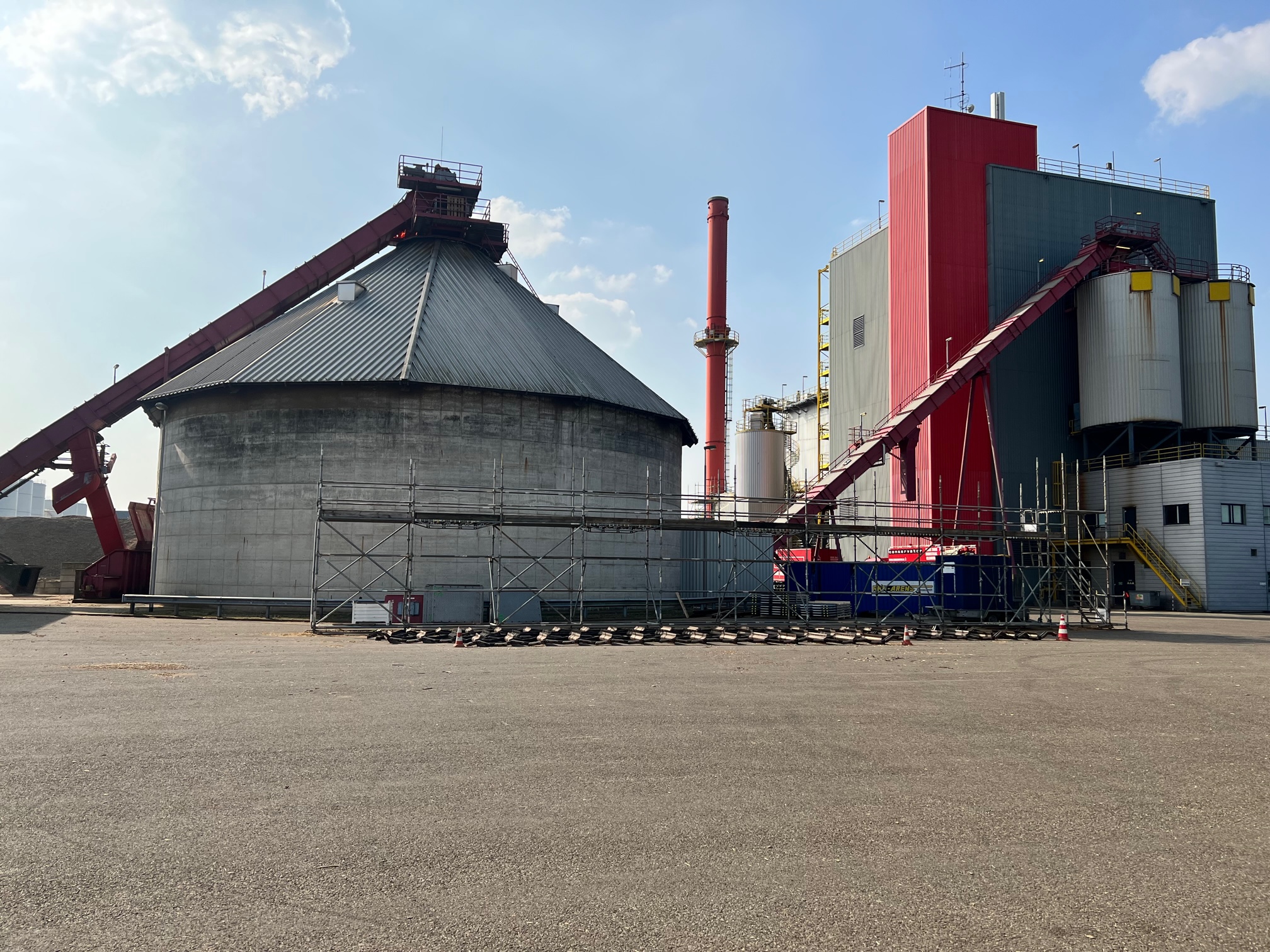 a large industrial building with a red and white building on the side.