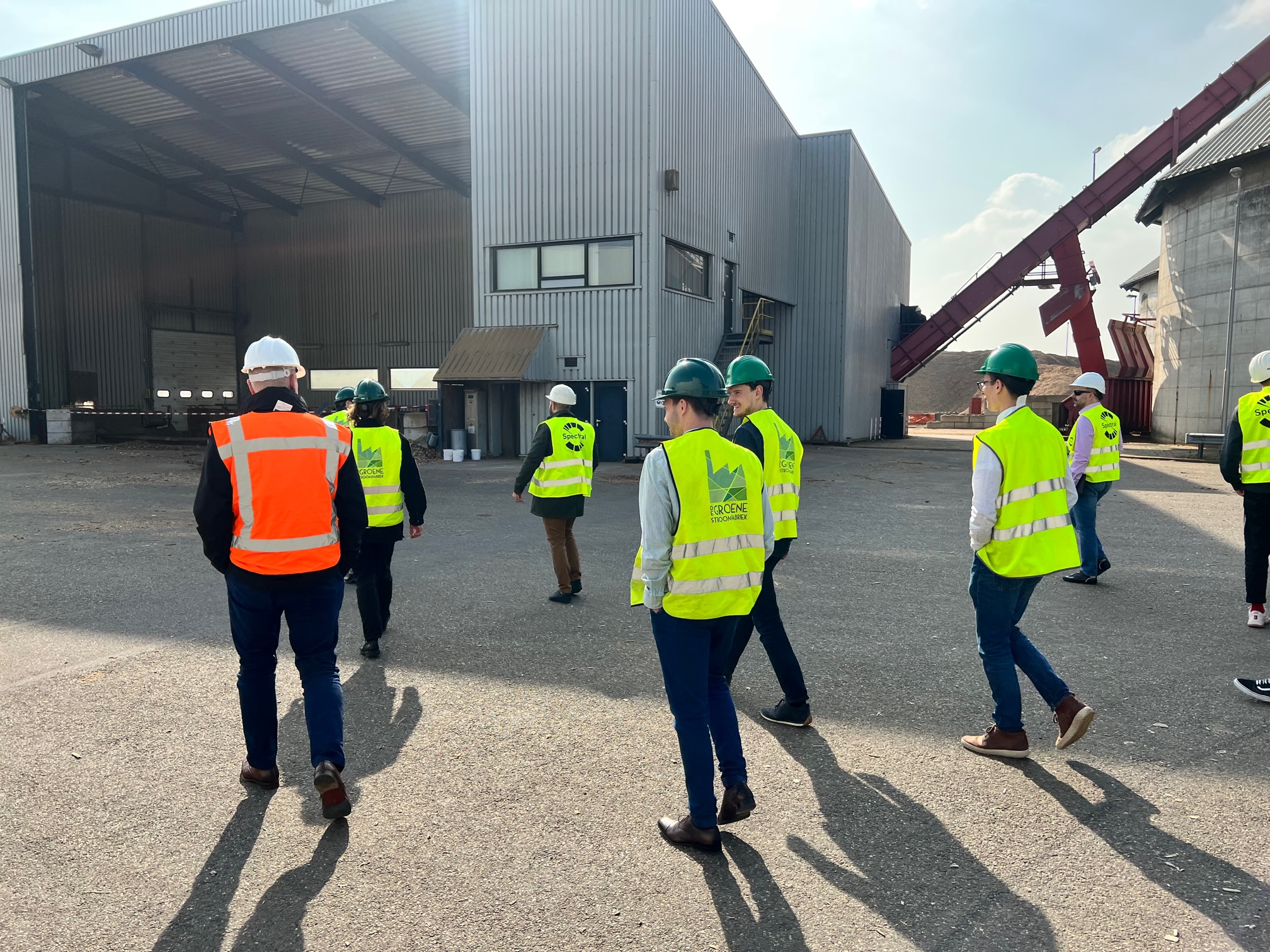 a group of people in safety vests standing in front of a building.