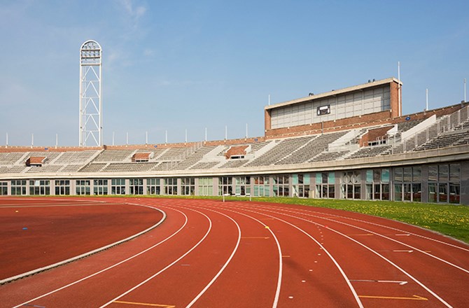 an empty stadium with a red track running through it.