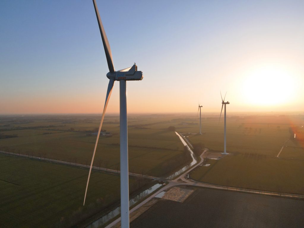 the sun is setting behind a wind farm.